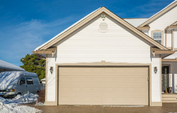 wide garage door of luxury house with concrete driveway and rv wagon parked nearby