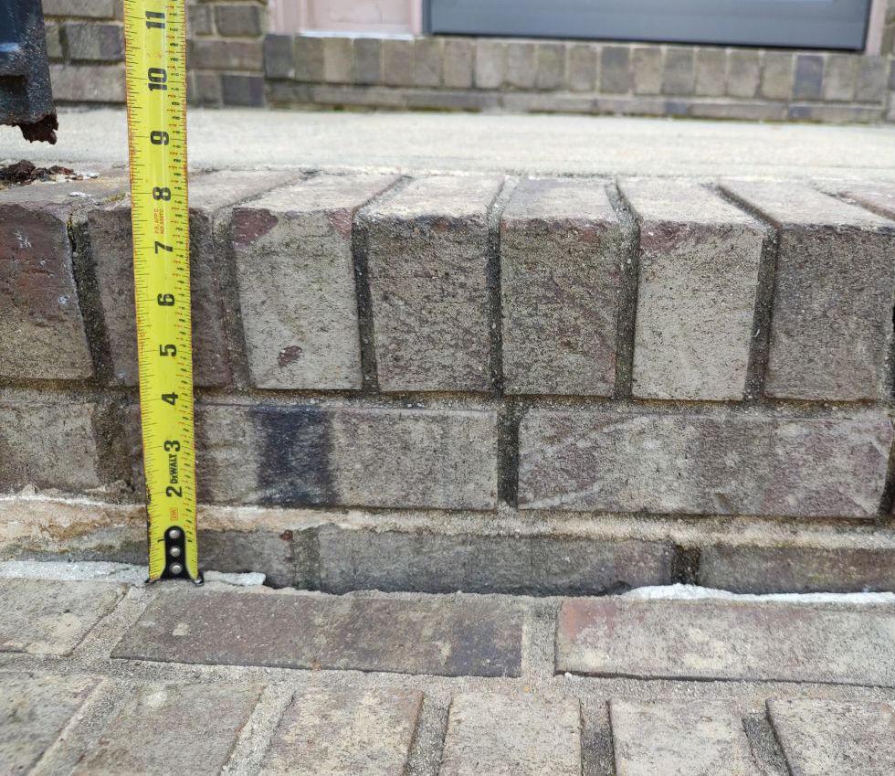 Brick steps with soil settlement and visible gap beneath the concrete.